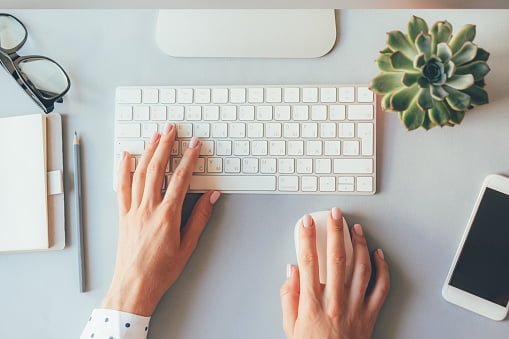Top view of the workplace, elegant female hands on the keyboard of a personal computer in the office or at home, suitable for both freelancing and office content. Business lady prints an article or blog post online.